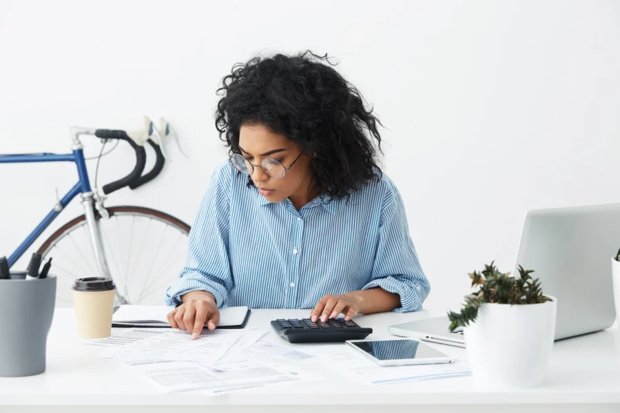 attractive-confident-young-businesswoman-with-curly-hairstyle-using-calculator-scaled